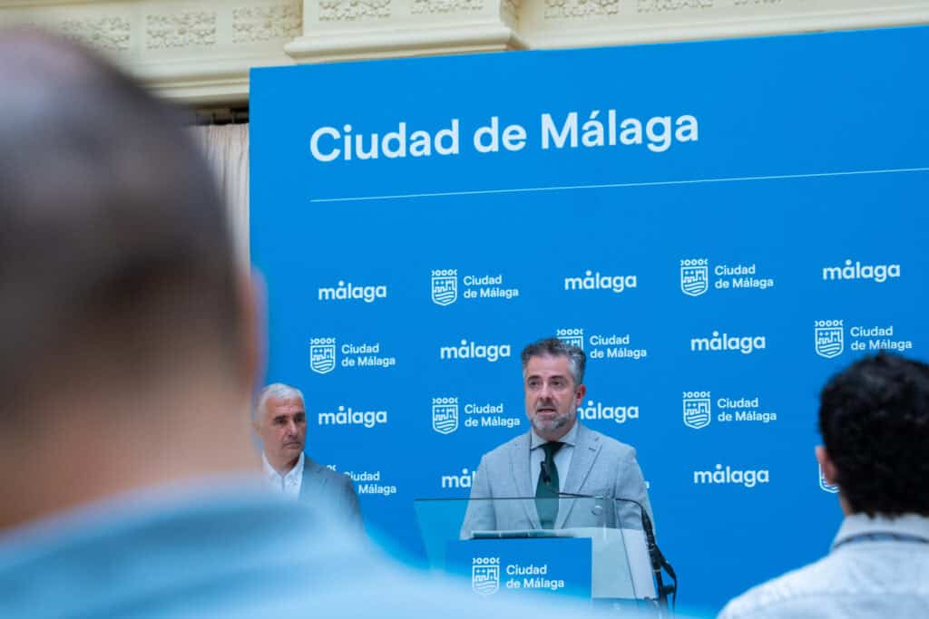 Hombre hablando en evento en Málaga con fondo de Ciudad de Málaga.