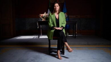 Patricia Cavada sentada en un escenario con bandera y decoraciones oficiales.
