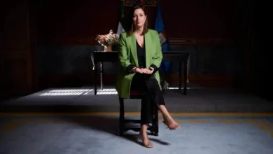 Patricia Cavada sentada en un escenario con bandera y decoraciones oficiales.