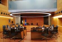 Sala de reuniones moderna con mesa redonda y banderas españolas y europeas.
