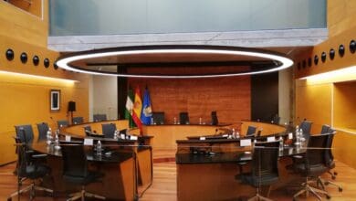 Sala de reuniones moderna con mesa redonda y banderas españolas y europeas.