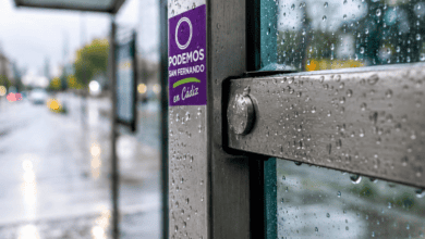 Cartel de Podemos en San Fernando en una parada de autobús lluviosa.