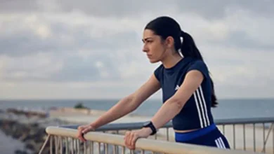 Mujer con ropa deportiva apoyada sobre una barandilla frente al mar