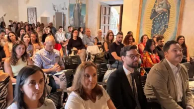 Público sentado durante una jornada en una sala con techo de madera y pinturas murales