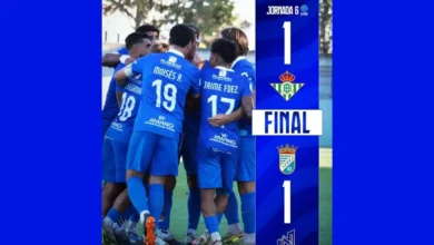 Futbolistas del Xerez CD con equipación azul se agrupan en un círculo durante una charla en el campo. A la derecha aparece un marcador gráfico del partido con el resultado final de 1-1.