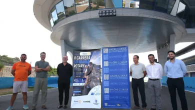 Seis hombres posan junto a carteles de la II Carrera Solidaria Rotary y Madre Coraje en el Circuito de Jerez.