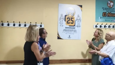 Cuatro personas aplauden frente a un cartel conmemorativo del 25 aniversario del Centro de Mayores El Abuelo.