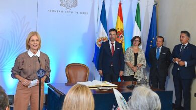 Acto oficial en el Ayuntamiento de Jerez con varias personas junto a la alcaldesa y las banderas institucionales
