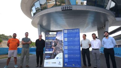 Seis hombres posan junto a carteles de la II Carrera Solidaria Rotary y Madre Coraje en el Circuito de Jerez.