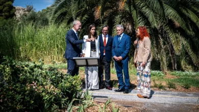 Cinco personas junto a un atril en una zona ajardinada con vegetación abundante y palmeras
