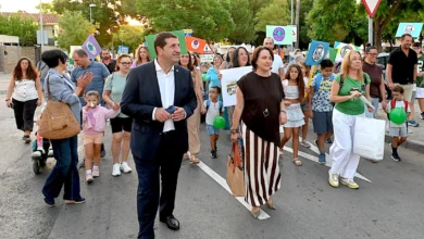 Grupo de personas caminando por una calle mientras sostiene carteles y globos verdes