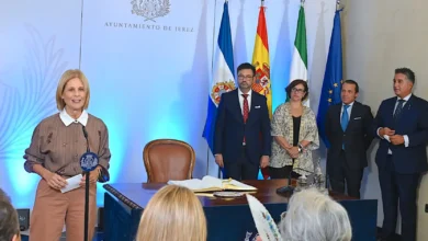 Acto oficial en el Ayuntamiento de Jerez con varias personas junto a la alcaldesa y las banderas institucionales