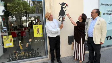 Tres personas junto a un escaparate decorado con figuras de títeres en un establecimiento del centro de Jerez.