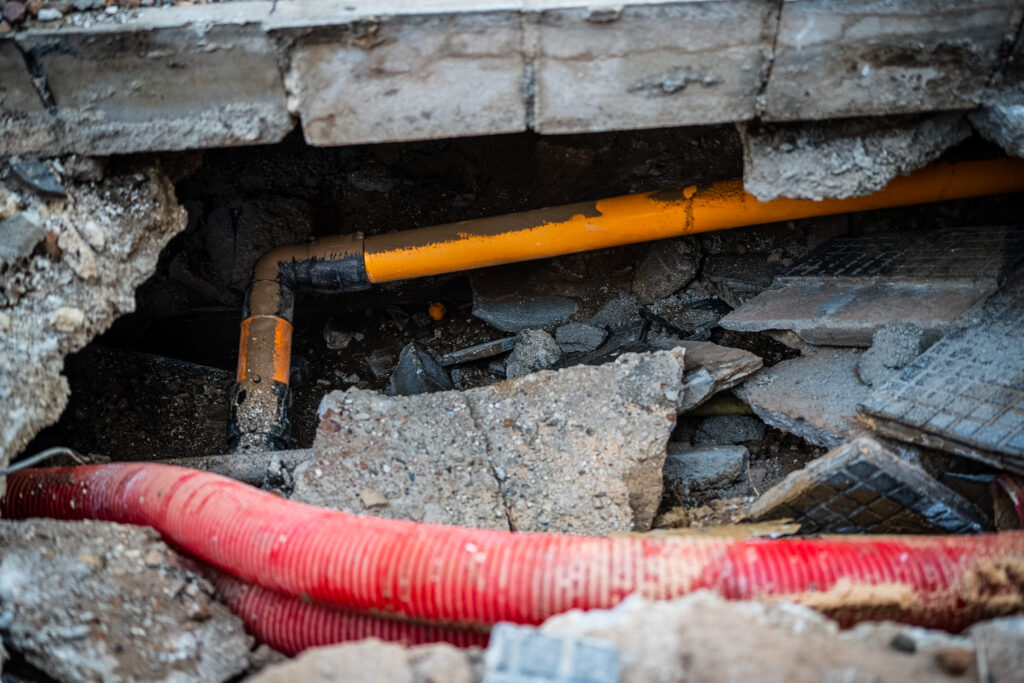 Obras de reparación con una excavadora y vallas azules en una calle urbana