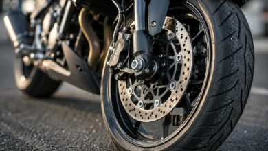 Primer plano de la rueda y el freno de una motocicleta sobre el asfalto, en una composición editorial relacionada con el accidente mortal en Jerez.