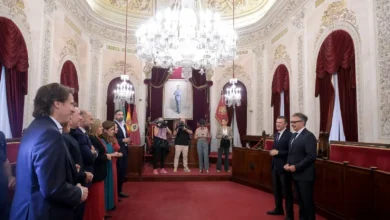 Representantes municipales y autonómicos reunidos en el Salón de Plenos del Ayuntamiento de Cádiz, con dos cargos públicos situados frente a la Corporación.