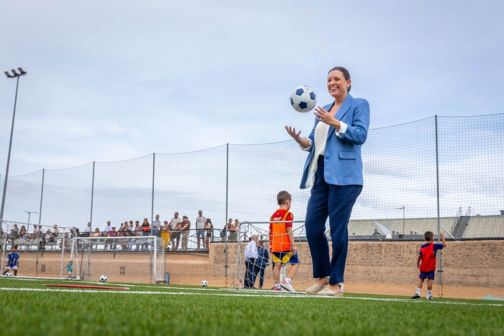 Vista amplia del campo de fútbol de Bahía Sur con césped artificial y varios grupos de jóvenes deportistas