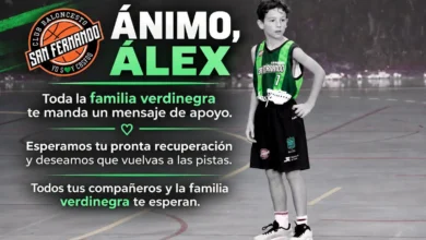 Primer plano de un balón de baloncesto sobre una pista deportiva, con su textura de cuero sintético y una canasta desenfocada al fondo.