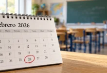 Primer plano de un calendario escolar abierto, un lápiz y material de escritura sobre una mesa de madera.