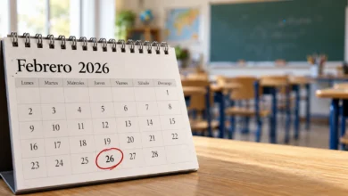Primer plano de un calendario escolar abierto, un lápiz y material de escritura sobre una mesa de madera.