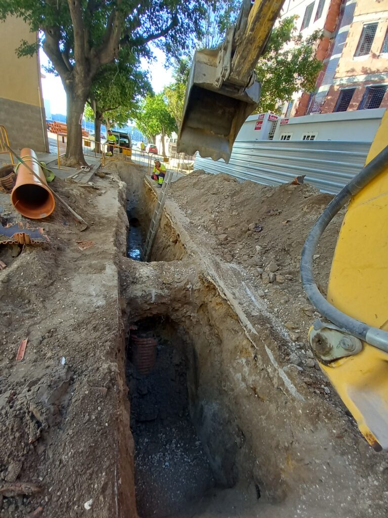 Zanja y maquinaria durante trabajos de canalización en una calle urbana