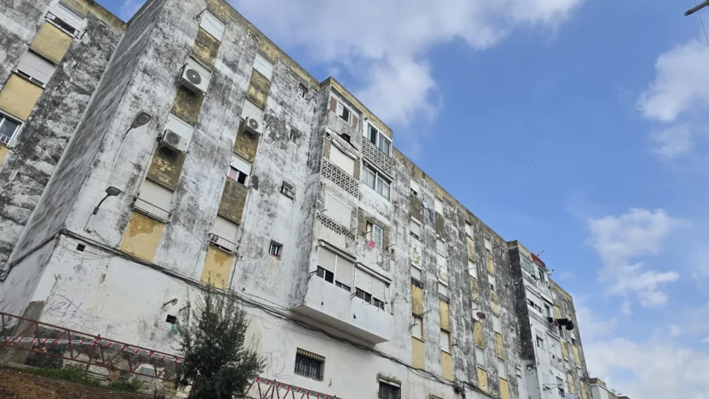 Primer plano de una superficie de hormigón y revestimiento envejecido con pequeñas grietas y bordes irregulares.
