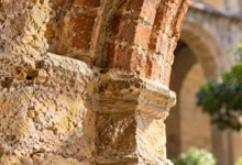 Detalle de piedra antigua y arco de ladrillo en un espacio arquitectónico histórico de inspiración andalusí.