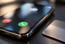 Primer plano de un teléfono móvil con una llamada entrante y la pantalla desenfocada sobre una mesa oscura.