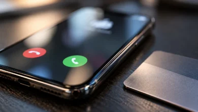 Primer plano de un teléfono móvil con una llamada entrante y la pantalla desenfocada sobre una mesa oscura.