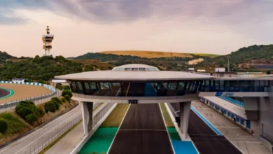 Vista elevada de un edificio acristalado sobre la pista del Circuito de Jerez, con una torre al fondo y zonas de asfalto a ambos lados.