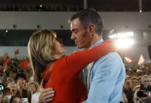 Pedro Sánchez y Begoña Gómez se abrazan ante un numeroso público durante un acto político.