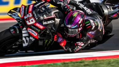 Piloto de MotoGP inclinado sobre su moto durante una curva, con el casco y el carenado en primer plano.