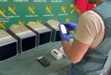 Agente de la Guardia Civil de espaldas junto a cuatro pantallas de navegación y varios dispositivos electrónicos sobre una mesa.