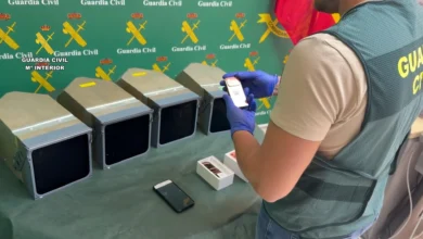 Agente de la Guardia Civil de espaldas junto a cuatro pantallas de navegación y varios dispositivos electrónicos sobre una mesa.