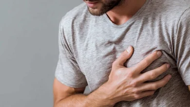Primer plano del torso de un hombre con camiseta gris que mantiene una mano apoyada sobre el pecho.