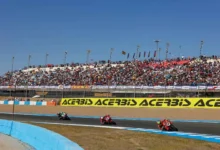 Tres motos de competición circulan por una curva del circuito ante las gradas llenas de espectadores.