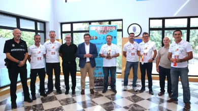 Grupo de hombres posando en el interior de un edificio junto a un cartel del Campeonato de España Mountain Bike 2026; varios llevan camisetas deportivas blancas y dos sostienen medallas.