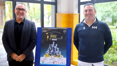 Dos hombres posan junto a un cartel de la XXX Media Maratón de Jerez 2026 en una sala con grandes ventanales.