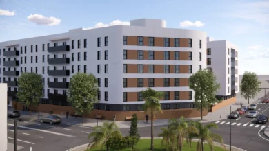 Recreación arquitectónica de un conjunto de edificios residenciales blancos con balcones oscuros, árboles, palmeras y calles con vehículos.