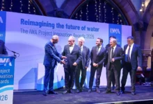 Varios participantes vestidos de traje durante una entrega de premios sobre el escenario de los IWA Project Innovation Awards 2026.