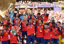 La selección española de fútbol celebra un título con el trofeo levantado y confeti en el estadio.