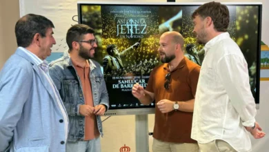 Cuatro hombres conversan delante de una pantalla que muestra el cartel de Así canta Jerez en Navidad en Sanlúcar de Barrameda.