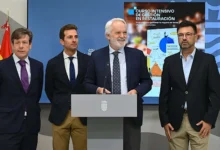Cuatro hombres posan ante un atril institucional en una sala con banderas y una pantalla sobre un curso intensivo de gestión en restauración.