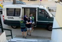Agentes de la Guardia Civil acompañan a una persona junto a la puerta lateral abierta de un furgón oficial.