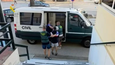 Agentes de la Guardia Civil acompañan a una persona junto a la puerta lateral abierta de un furgón oficial.