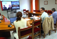 Reunión municipal telemática para revisar el plan contra el cambio climático de Jerez, con varios asistentes alrededor de una mesa y una pantalla de videoconferencia.