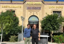Dos hombres posan delante de la entrada del Restaurante Don Pepe, con una fachada de piedra, vegetación y el rótulo del establecimiento.