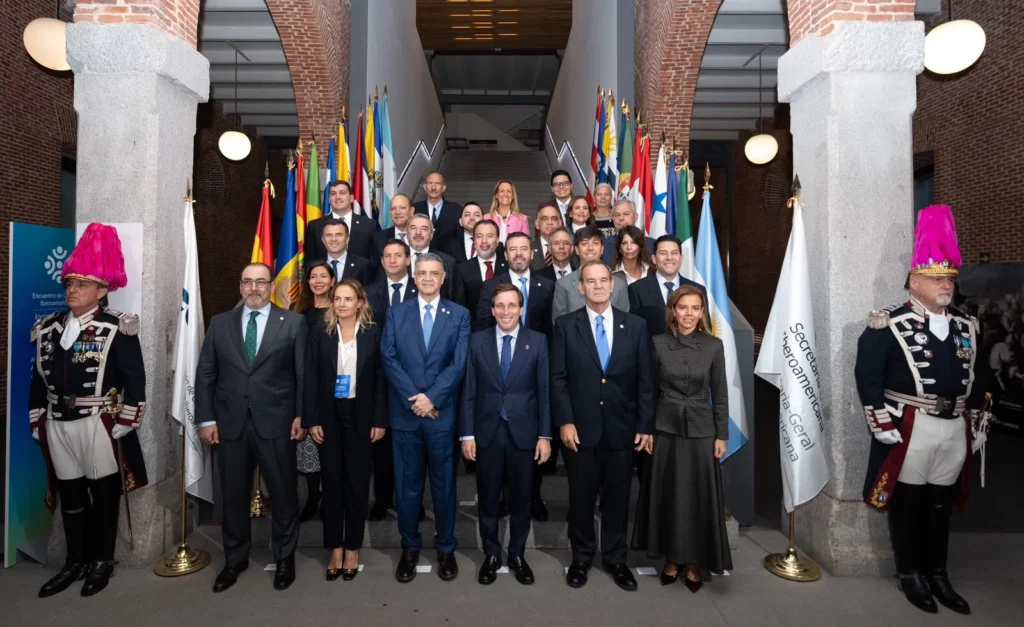 Primer plano de un micrófono de conferencia con soporte metálico sobre una mesa y fondo azul desenfocado.