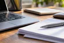 Primer plano de un teclado, documentos de trabajo y un bolígrafo sobre una mesa de oficina.