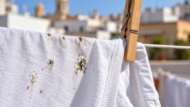 Primer plano de ropa blanca tendida con pequeñas manchas de excrementos de paloma y una pinza de madera.